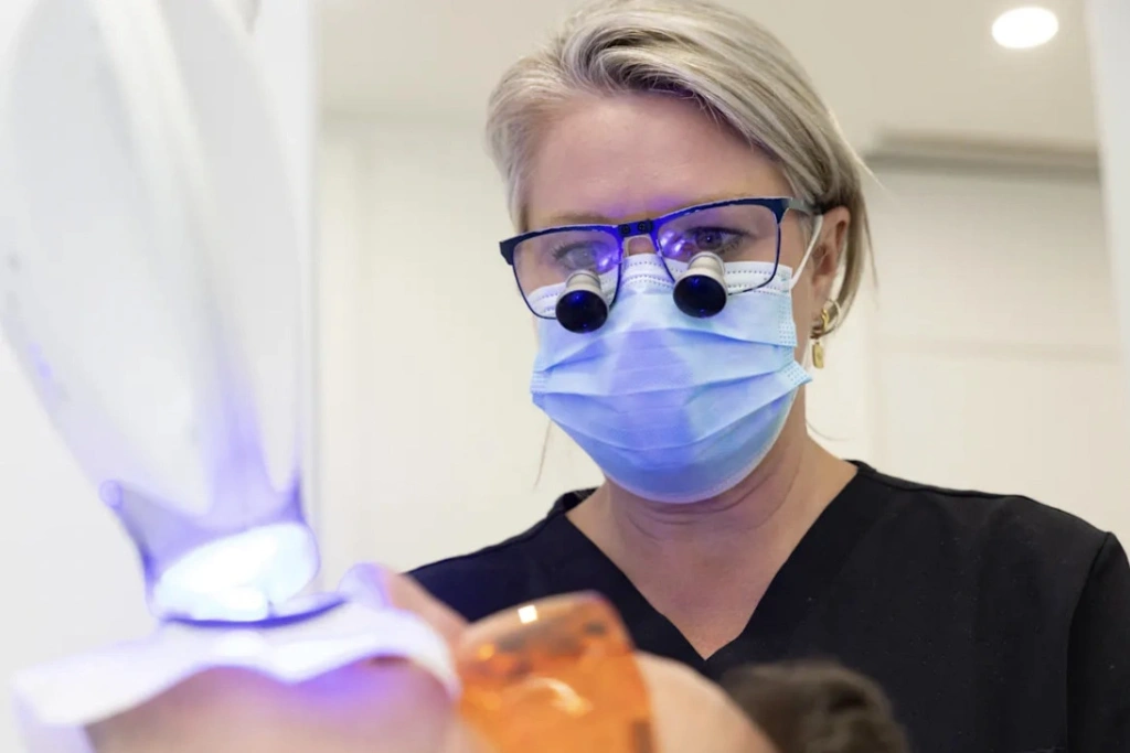 Dental hygienist Charmaine Maher watches as the peroxide takes effect on Carre’s teeth. JANIE BARRETT